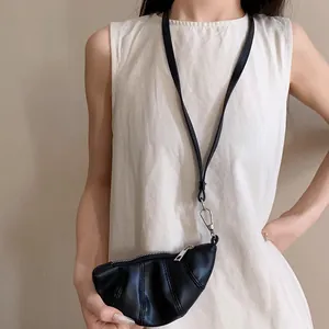 Primer plano de un collar monedero de cuero sintético negro con forma de croissant en modelo