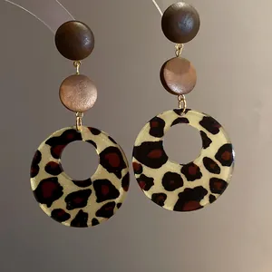 Close-up of retro leopard print hoop earrings with wooden studs and golden links.