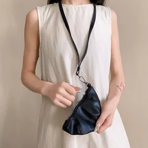 Detalle de monedero de croissant en cuero sintético negro usado como collar