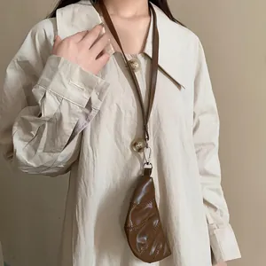 Detalle de un monedero de cuero marrón vintage con forma de cuerno usado como accesorio de cuello