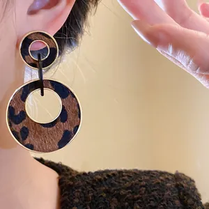 Macro detail of leopard print double circle drop earrings with vintage Maillard style