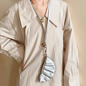 Modelo con collar de mini bolsa de cuero sintético plateado sobre una camisa beige