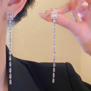 Detailed view of silver needle tassel earrings featuring rectangular clear zircons
