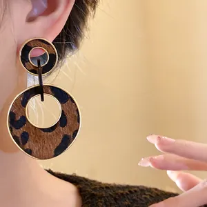 Close-up detail of retro leopard print double circle dangle earrings worn on an ear.