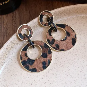Detail of leopard print earrings with gold-rimmed circular texture on a ceramic plate