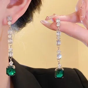 Detail shot of long tassel earrings with clear zirconia and green emerald-cut crystal