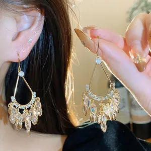 Detail view of 18k gold plated drop earrings featuring sparkling zircon leaf tassels