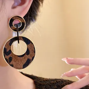 Close-up detail shot of vintage leopard print circular drop earrings with gold trim.