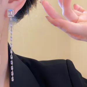 Elegant close-up detail of silver tassel earrings with square cubic zirconia on model