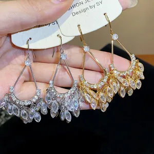 Detailed view of gold and silver plated teardrop tassel earrings with cubic zirconia.