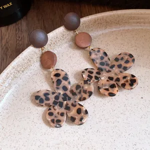 Detailed close-up of retro leopard print flower earrings with wooden beads on a ceramic plate