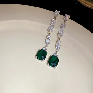 Detail view of elegant square emerald green stone drop earrings with sparkling white zircons