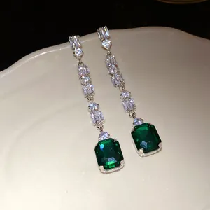 Macro detail of elegant emerald green square zircon drop earrings with silver finish