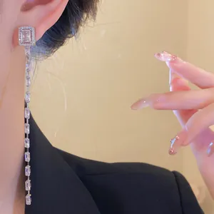 Close-up of silver long tassel earrings with sparkling rectangular zircon stones