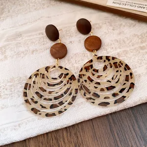 Close-up of retro Maillard style leopard print earrings featuring textured wooden disc accents.