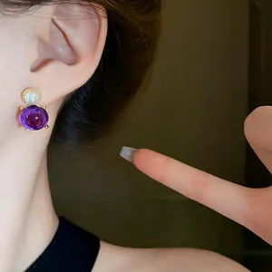 Elegant French-style purple gemstone and pearl stud earrings shown on a model's ear
