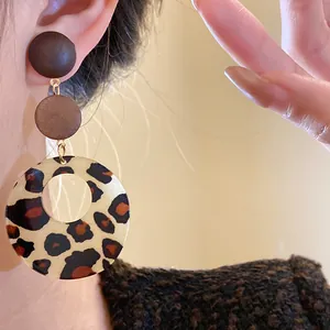 Close-up view of vintage leopard print wood drop earrings worn in retro Maillard style