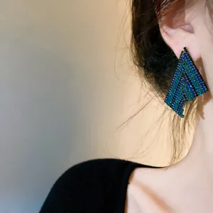 Macro view of geometric trapezoid earrings with blue and green chevron stone patterns