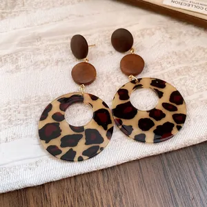 Detailed macro view of vintage leopard print acrylic drop earrings with brown wooden discs