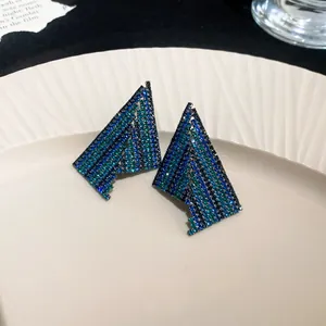 Detailed macro view of geometric stud earrings with shimmering blue and green rhinestones