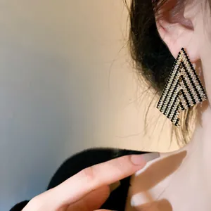 Elegant black and white chevron drop earrings worn by model with silver needles.