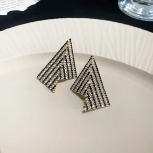 Close-up detail of geometric earrings with black and white rhinestones on beige plate
