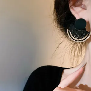 Close-up of elegant fan-shaped black earrings with rhinestone details worn by model