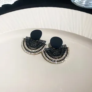 Close-up detail of fan-shaped earrings with intricate engraving and sparkling rhinestones.