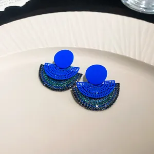 Close-up of cobalt blue fan-shaped earrings with green and blue rhinestone details