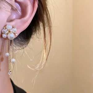 Close-up detail showing the intricate zircon tassel and pearl flower design of the earring