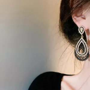 Detailed view of ornate fan-shaped metal earrings with rhinestone accents on ear