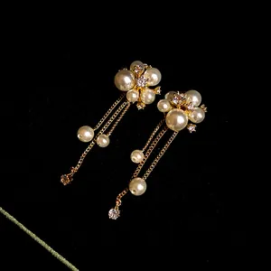 Macro view of elegant gold-toned tassel earrings featuring pearl flowers and sparkling crystals