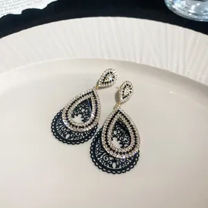 Close-up detail of teardrop earrings featuring sparkling crystals and black filigree metal