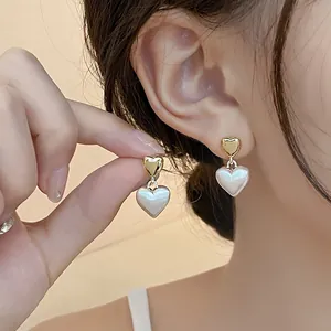 Close-up detail view of elegant French style heart earrings with gold and pearl elements