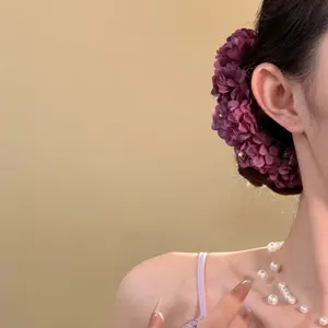 Vista detallada de un peine para el cabello con flores moradas y un collar de perlas blancas