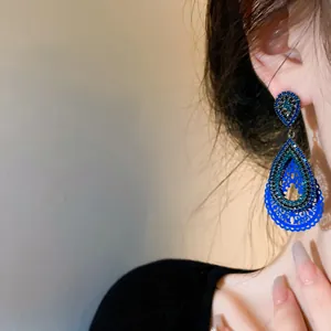 Close-up detail of vintage blue carved fan-shaped earrings with rhinestones on model