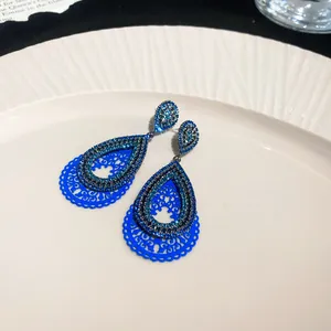 Detailed close-up of blue hollow-out teardrop earrings with shimmering blue rhinestones.
