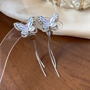 Close-up detail of silver zircon butterfly tassel clip-on earrings with blue enamel wings