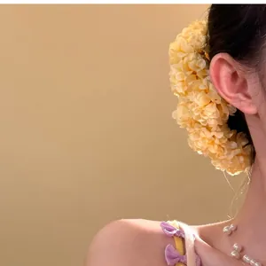 Vista detallada de una elegante horquilla de flores de tela amarilla en el pelo