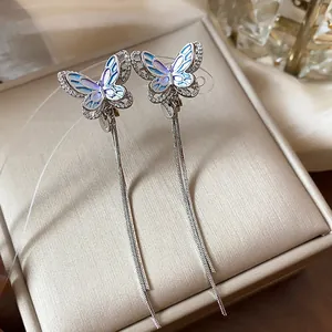 Macro view of blue enamel butterfly ear clips with elegant long silver chain tassels