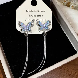 Macro view of iridescent butterfly ear clips with long zircon tassels in jewelry box.