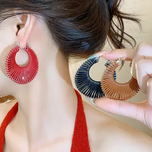 Close-up of stylish round woven hoop earrings in red, black, and brown colors