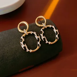 Vintage style gold-plated circular earrings with black and white cow print resin inlay