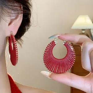Detailed view of red woven hoop earrings with gold accents on model skin
