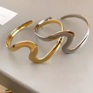 Elegant minimalist wavy metal open bangle cuff bracelet in polished gold and silver