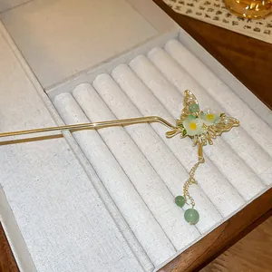 Detailed view of an elegant butterfly hairpin with green flowers and pearl tassels.