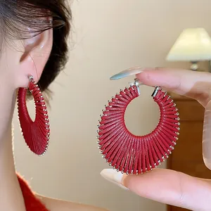 Detailed macro view of red woven hollow hoop earrings with silver metallic bead edges