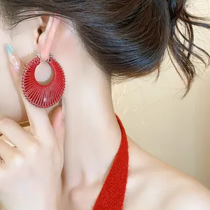 Detailed close-up view of a stylish red woven hollow hoop earring on an Asian model