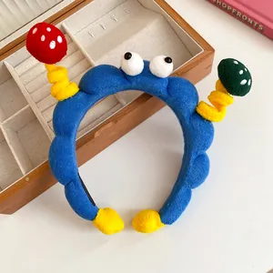 Detailed view of a funny blue plush cartoon headband with googly eyes and mushroom antennas.