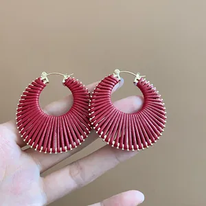 Detail view of red fan-shaped thread-wrapped hoop earrings with gold-tone hardware